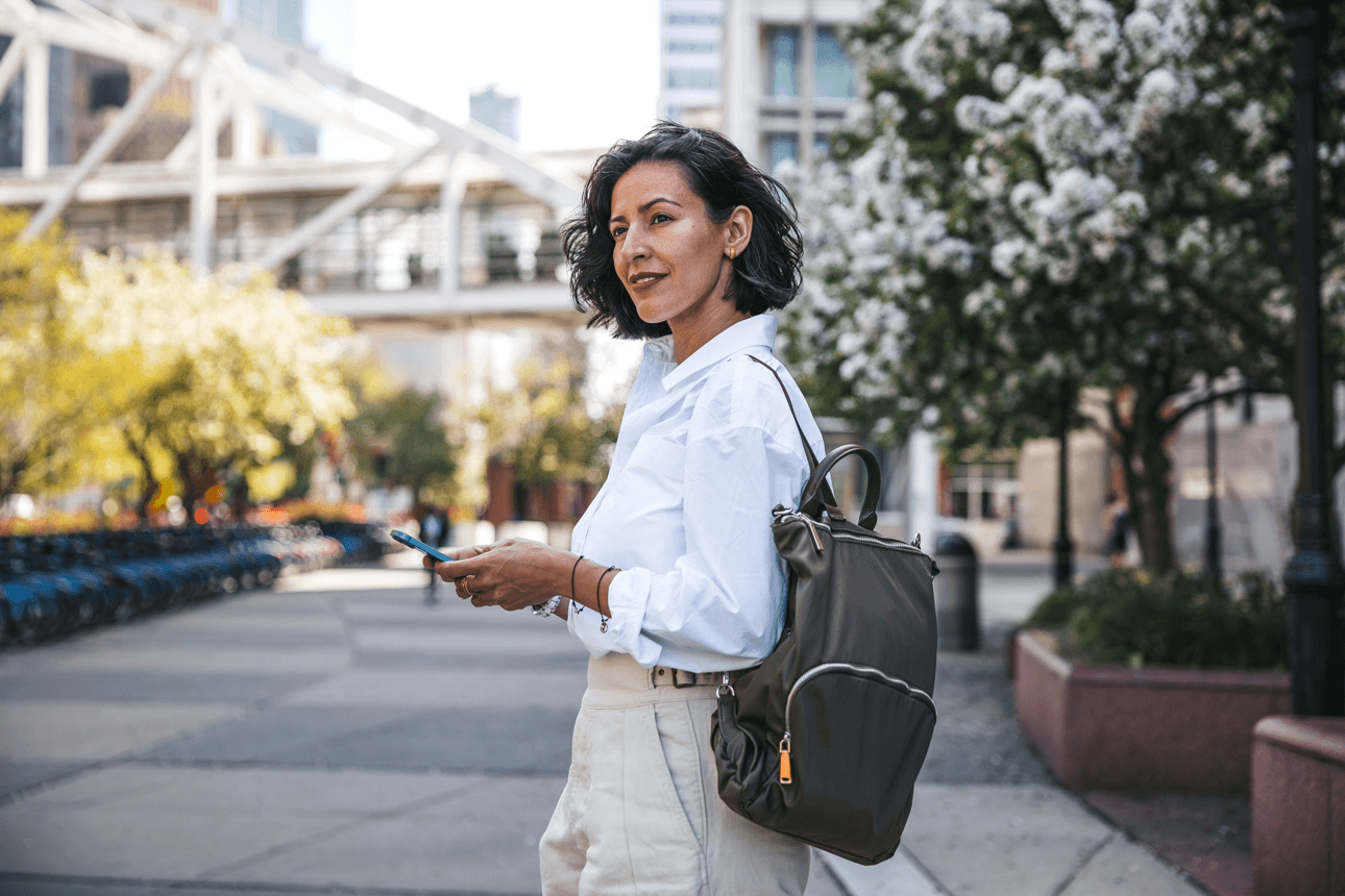 Female walking down the street with a backpack on her phone