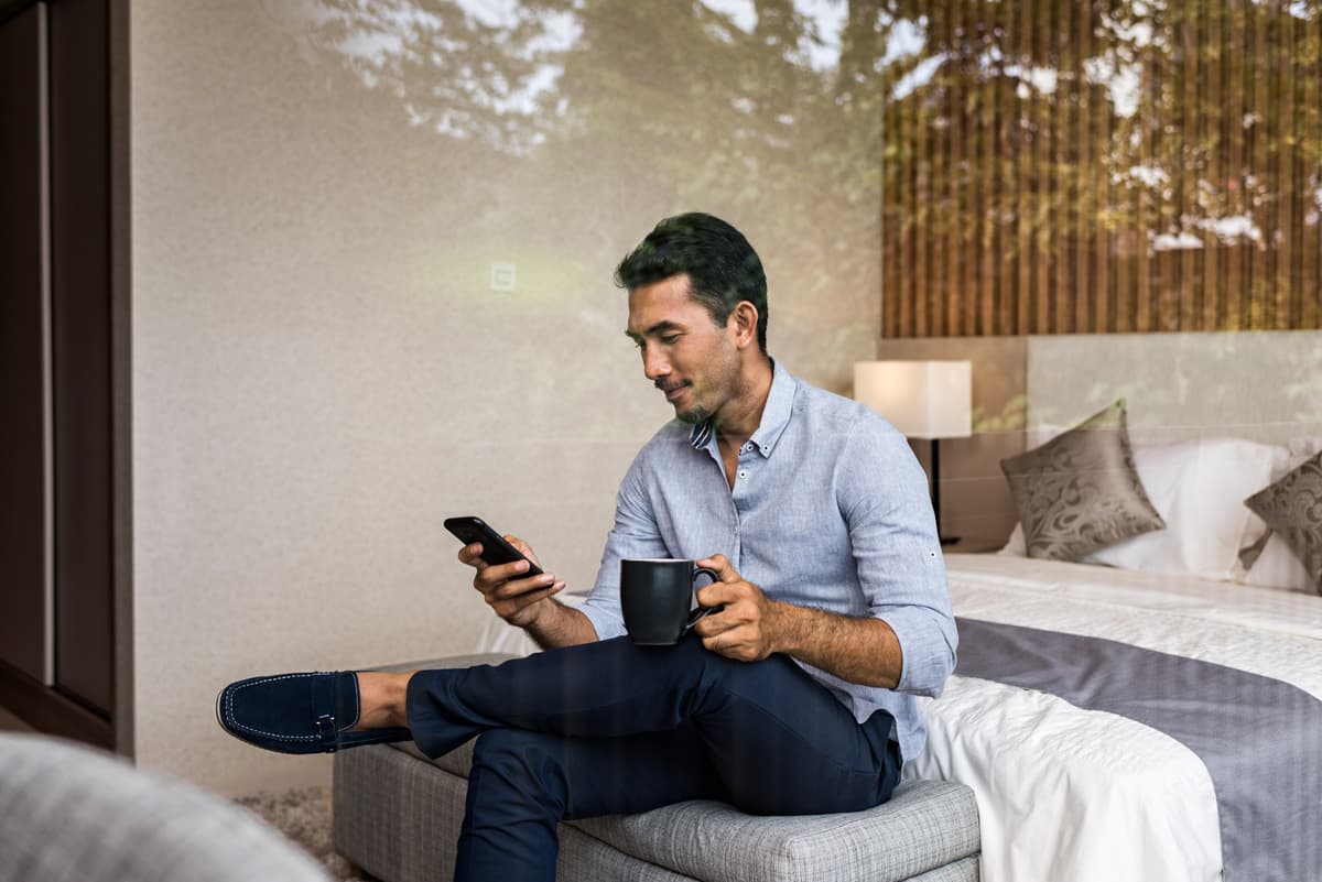 Man sitting on the end of his bed looking at his phone