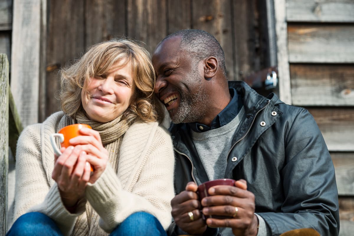Man and women sitting outside there house with a hot drink