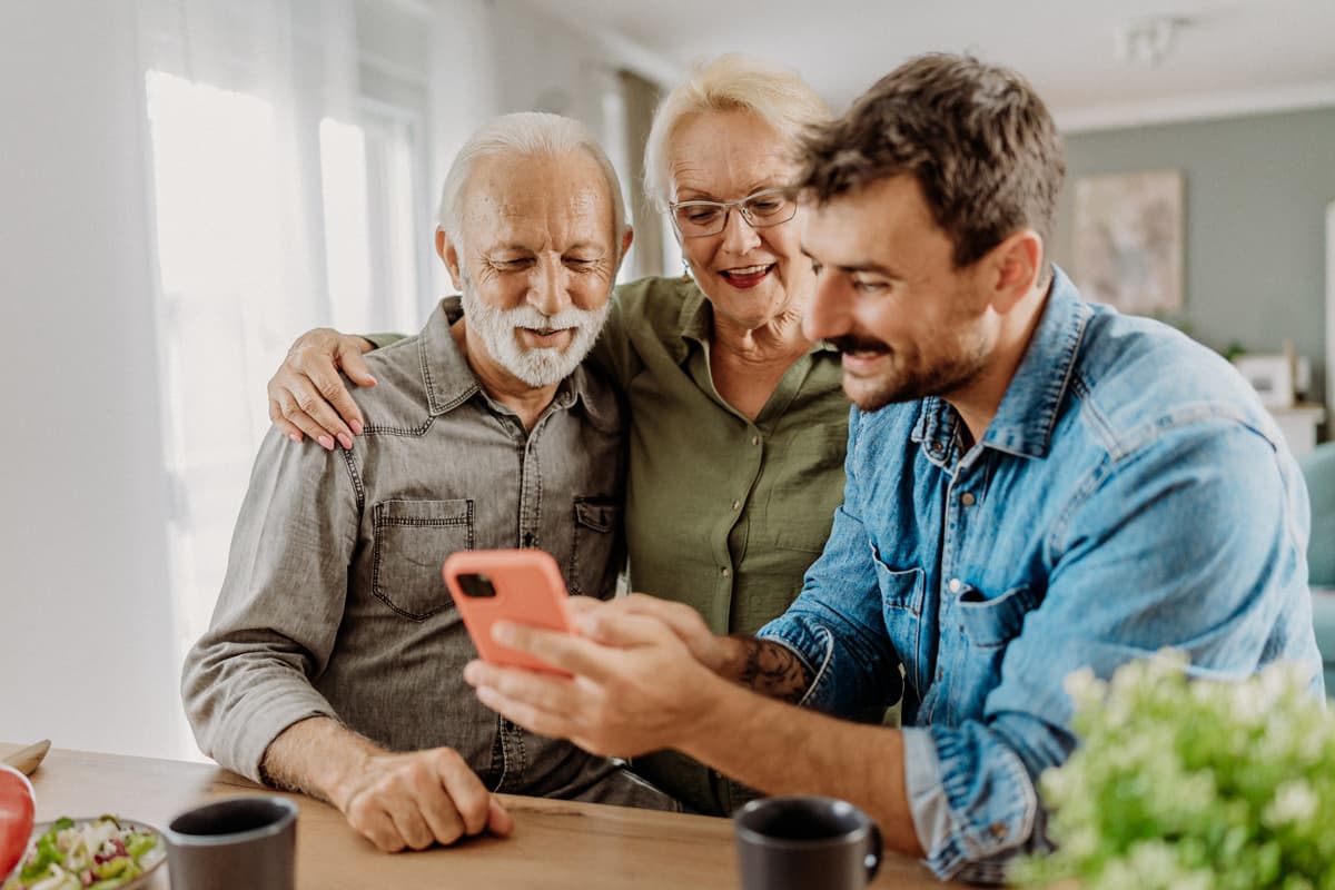 Couple with younger man looking at his phone smiling