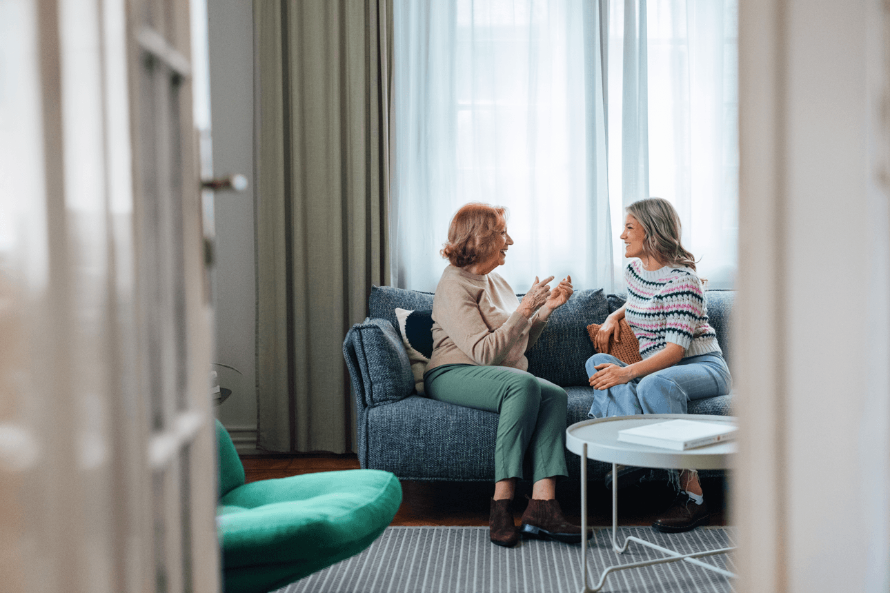 Younger and older female chatting on the sofa